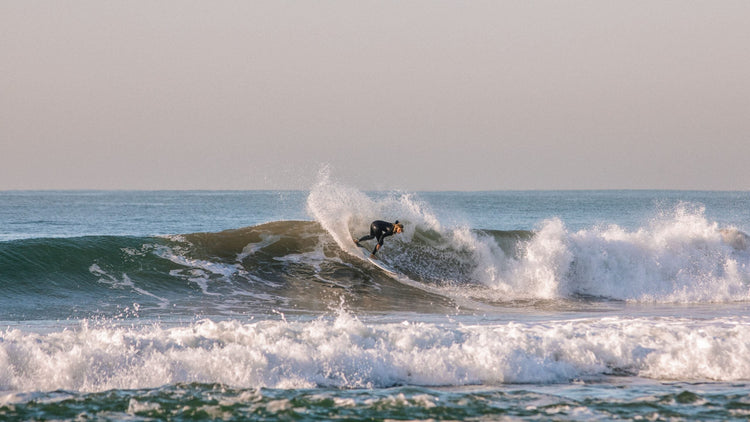 Surfer wearing a women's cold water wetsuit surfing in the ocean.