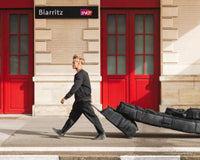 Surfer walking down the street pulling his wheeled DB Coffin surfboard travel bag.